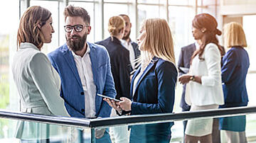 Männer und Frauen stehen an Geländer, im Gespräch