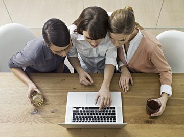 Drei Frauen sitzen mit einem Laptop am Tisch