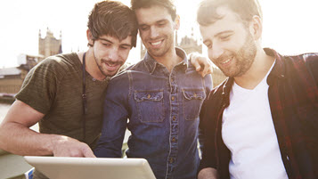 Drei junge Männer schauen gemeinsam auf ein Tablet