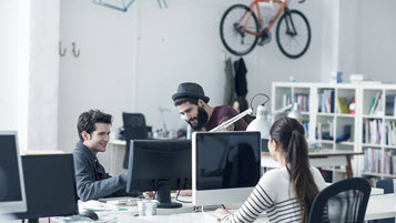Junge Menschen sitzen in einem Start-up-Büro, in dem ein Rennrad an der Wand hängt