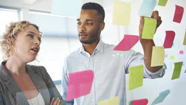 Frau und Mann hängen Post-its an ein Fenster