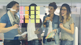 Junge Menschen kleben Post-its an ein Glasboard