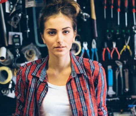 Eine Handwerkerin vor einer Werkzeugwand.